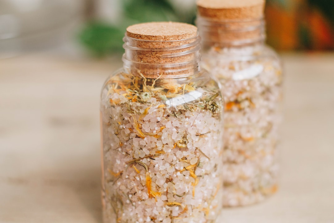 A wellness-themed setting showing a DIY Himalayan salt scrub in a glass jar with a wooden spoon and dried flowers